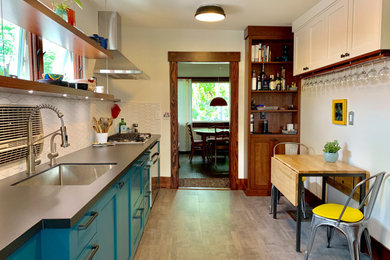 Example of a small eclectic galley vinyl floor and gray floor enclosed kitchen design in Salt Lake City with an undermount sink, shaker cabinets, white backsplash, ceramic backsplash, stainless steel appliances and black countertops