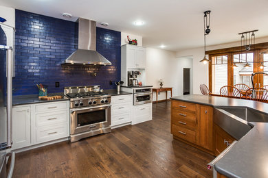 Inspiration for a medium sized eclectic l-shaped open plan kitchen in Providence with a belfast sink, beaded cabinets, white cabinets, engineered stone countertops, blue splashback, brick splashback, stainless steel appliances, dark hardwood flooring and an island.