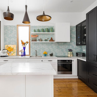 Inspiration for a mid-sized transitional l-shaped kitchen in Melbourne with an undermount sink, shaker cabinets, black cabinets, green splashback, porcelain splashback, medium hardwood floors, with island, brown floor and grey benchtop.