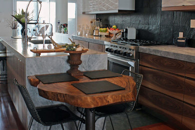 Mid-sized eclectic galley slate floor eat-in kitchen photo in Toronto with a drop-in sink, flat-panel cabinets, medium tone wood cabinets, marble countertops, gray backsplash, slate backsplash, stainless steel appliances and an island