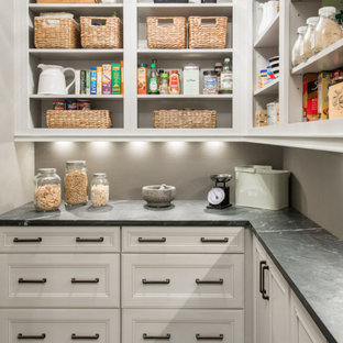 Design ideas for a transitional l-shaped kitchen pantry in St Louis with white cabinets, soapstone benchtops, porcelain floors, open cabinets, grey splashback, black floor and black benchtop.