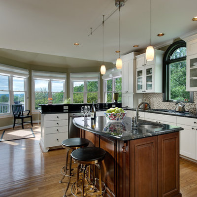 Eat-in kitchen - large traditional u-shaped medium tone wood floor and brown floor eat-in kitchen idea in DC Metro with stainless steel appliances, recessed-panel cabinets, white cabinets, multicolored backsplash and an island
