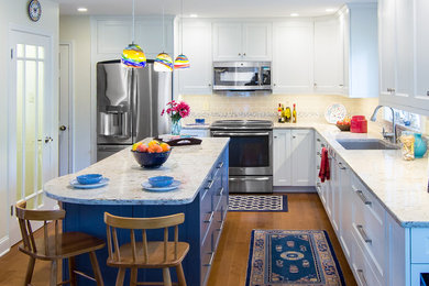 Inspiration for a large eclectic l-shaped medium tone wood floor and brown floor eat-in kitchen remodel in Philadelphia with an undermount sink, recessed-panel cabinets, white cabinets, quartz countertops, multicolored backsplash, ceramic backsplash, stainless steel appliances, an island and beige countertops