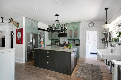 Large cottage l-shaped medium tone wood floor eat-in kitchen photo in Jacksonville with a farmhouse sink, shaker cabinets, green cabinets, stainless steel appliances and two islands