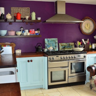 Photo of a mid-sized country l-shaped eat-in kitchen in Wiltshire with a drop-in sink, shaker cabinets, blue cabinets, wood benchtops, stainless steel appliances, ceramic floors, no island and beige floor.
