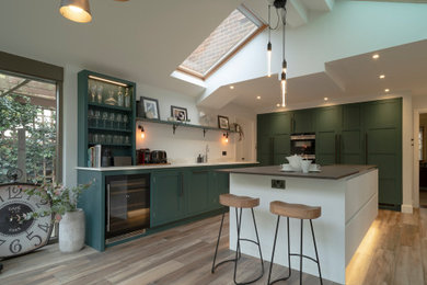 サリーにある高級な中くらいなエクレクティックスタイルのおしゃれなアイランドキッチン (緑のキャビネット、磁器タイルの床) の写真