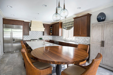 Large classic l-shaped kitchen/diner in Chicago with a submerged sink, recessed-panel cabinets, wood worktops, stainless steel appliances, travertine flooring, an island and dark wood cabinets.
