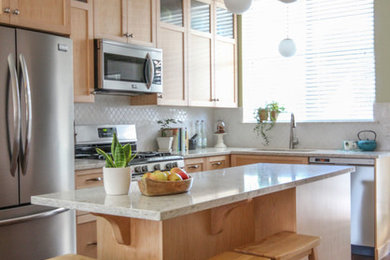 Kitchen - mid-sized traditional l-shaped medium tone wood floor kitchen idea in Vancouver with a double-bowl sink, shaker cabinets, light wood cabinets, quartz countertops, white backsplash, porcelain backsplash, stainless steel appliances and an island