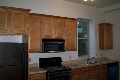 Foto de cocina comedor lineal clásica con fregadero encastrado, armarios con paneles con relieve, puertas de armario de madera clara y electrodomésticos de acero inoxidable