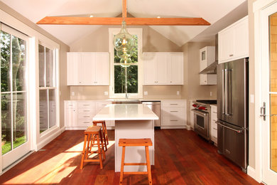 Inspiration for a mid-sized eclectic l-shaped dark wood floor and red floor eat-in kitchen remodel in Boston with a farmhouse sink, flat-panel cabinets, white cabinets, quartz countertops, stainless steel appliances, an island and multicolored countertops