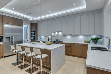 Inspiration for a large modern u-shaped kitchen/diner in Vancouver with a double-bowl sink, flat-panel cabinets, grey cabinets, engineered stone countertops, white splashback, engineered quartz splashback, stainless steel appliances, light hardwood flooring, an island, beige floors, white worktops and a drop ceiling.