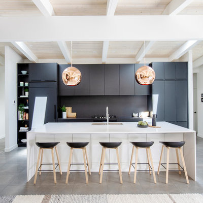 Open concept kitchen - large mid-century modern single-wall gray floor and concrete floor open concept kitchen idea in Vancouver with an undermount sink, flat-panel cabinets, black cabinets, black backsplash, paneled appliances, an island, black countertops and quartz countertops