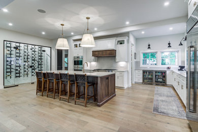 Kitchen - large transitional light wood floor kitchen idea in Cleveland with an undermount sink, shaker cabinets, white cabinets, quartzite countertops, gray backsplash, ceramic backsplash, stainless steel appliances, an island and white countertops