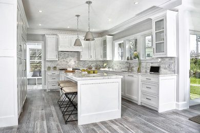 Mid-sized beach style u-shaped light wood floor and gray floor eat-in kitchen photo in New York with an undermount sink, recessed-panel cabinets, white cabinets, multicolored backsplash, paneled appliances, an island, marble countertops and marble backsplash