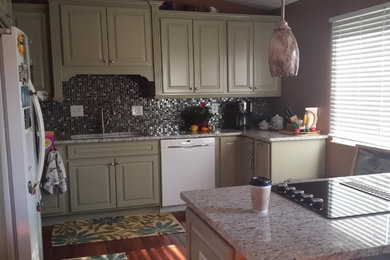 This is an example of a small classic galley kitchen in Cincinnati with raised-panel cabinets, green cabinets, granite worktops, metallic splashback, glass tiled splashback, white appliances, a submerged sink and medium hardwood flooring.