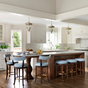 Elegant l-shaped dark wood floor and brown floor kitchen photo in Minneapolis with raised-panel cabinets, white cabinets, white backsplash, subway tile backsplash, an island and white countertops