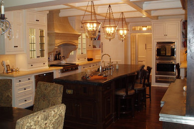 Example of a huge classic u-shaped medium tone wood floor enclosed kitchen design in Minneapolis with a farmhouse sink, beaded inset cabinets, white cabinets, soapstone countertops, beige backsplash, subway tile backsplash and paneled appliances