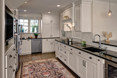 Eat-in kitchen - mid-sized traditional galley porcelain tile and brown floor eat-in kitchen idea in Minneapolis with an undermount sink, shaker cabinets, white cabinets, quartz countertops, white backsplash, ceramic backsplash, stainless steel appliances and a peninsula