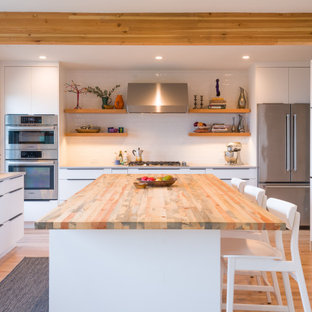 Esempio di una cucina minimalista di medie dimensioni con ante lisce, ante bianche, top in legno, paraspruzzi bianco, paraspruzzi con piastrelle diamantate, elettrodomestici in acciaio inossidabile, parquet chiaro, lavello sottopiano, isola, pavimento marrone, top bianco e soffitto a volta