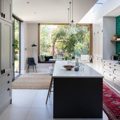 Inspiration for a large contemporary gray floor open concept kitchen remodel in London with solid surface countertops, green backsplash, an island, an undermount sink, recessed-panel cabinets, gray cabinets and white countertops