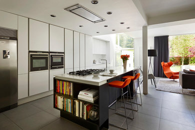 Inspiration for a modern galley open plan kitchen in Manchester with flat-panel cabinets, white cabinets, stainless steel appliances, an island and grey floors.