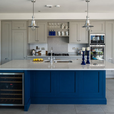 Inspiration for a large transitional galley porcelain tile open concept kitchen remodel in Dublin with an integrated sink, recessed-panel cabinets, gray cabinets, quartz countertops, gray backsplash and an island