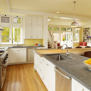 Design ideas for a traditional u-shaped open plan kitchen in San Francisco with an undermount sink, shaker cabinets, white cabinets, concrete benchtops, yellow splashback, subway tile splashback, stainless steel appliances, light hardwood floors and with island.