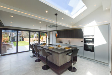 Inspiration for a large contemporary single-wall enclosed kitchen in London with flat-panel cabinets, grey cabinets, quartz worktops, white splashback, stone slab splashback, stainless steel appliances, an island and white worktops.