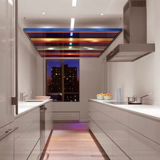 Mid-sized contemporary enclosed kitchen photos - Inspiration for a mid-sized contemporary galley light wood floor enclosed kitchen remodel in San Francisco with flat-panel cabinets, white cabinets, no island, an undermount sink, solid surface countertops, white backsplash and stainless steel appliances
