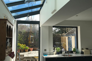 Small contemporary kitchen/diner in Cardiff with a single-bowl sink, shaker cabinets, blue cabinets, glass sheet splashback, stainless steel appliances, ceramic flooring, grey floors and white worktops.