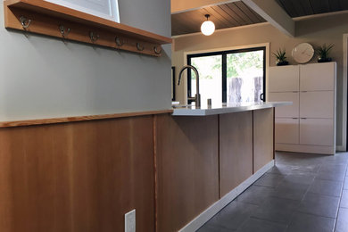 Example of a mid-sized minimalist galley ceramic tile open concept kitchen design in San Francisco with an undermount sink, flat-panel cabinets, light wood cabinets, solid surface countertops, white backsplash, stone slab backsplash, stainless steel appliances and no island