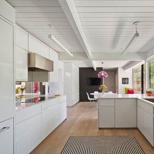 Esempio di una cucina parallela moderna con ante lisce, ante bianche, paraspruzzi con lastra di vetro e elettrodomestici da incasso
