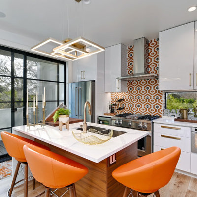 Trendy galley medium tone wood floor and brown floor kitchen photo in Austin with an undermount sink, flat-panel cabinets, white cabinets, multicolored backsplash, stainless steel appliances, an island and white countertops