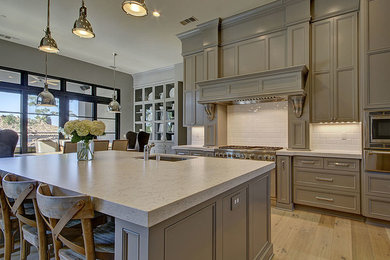 Mid-sized transitional l-shaped light wood floor and beige floor open concept kitchen photo in Sacramento with an undermount sink, gray cabinets, quartz countertops, white backsplash, stainless steel appliances, an island, recessed-panel cabinets and ceramic backsplash