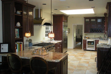 Example of a mid-sized l-shaped limestone floor open concept kitchen design in Phoenix with raised-panel cabinets, dark wood cabinets, marble countertops and stainless steel appliances