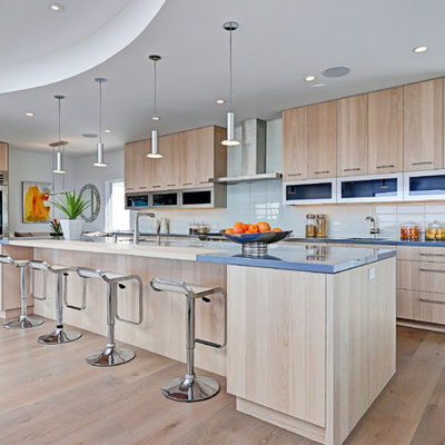 Open concept kitchen - large contemporary light wood floor open concept kitchen idea in Los Angeles with a drop-in sink, flat-panel cabinets, light wood cabinets, quartzite countertops, white backsplash, glass tile backsplash, stainless steel appliances and an island