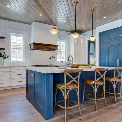 Kitchen - coastal light wood floor and beige floor kitchen idea in Los Angeles with shaker cabinets, blue cabinets, white backsplash, subway tile backsplash, paneled appliances, an island and white countertops