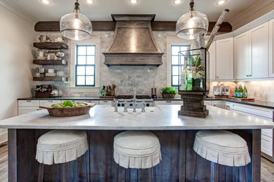 Example of a large classic l-shaped medium tone wood floor open concept kitchen design in Little Rock with a farmhouse sink, shaker cabinets, white cabinets, marble countertops, white backsplash, stainless steel appliances and an island