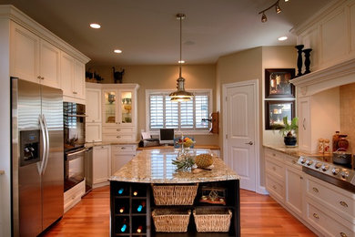 Immagine di una grande cucina classica con lavello sottopiano, ante nere, top in granito, paraspruzzi beige, elettrodomestici in acciaio inossidabile e pavimento in legno massello medio