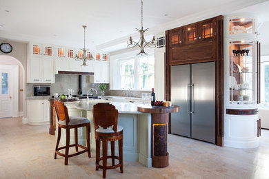 На фото: угловая кухня в классическом стиле с фасадами в стиле шейкер, белыми фасадами, серым фартуком, островом и мойкой у окна с
