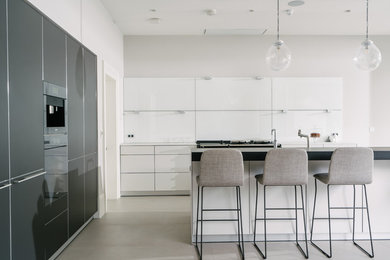 Photo of a large modern l-shaped kitchen in Belfast with flat-panel cabinets, porcelain flooring, an island and grey floors.