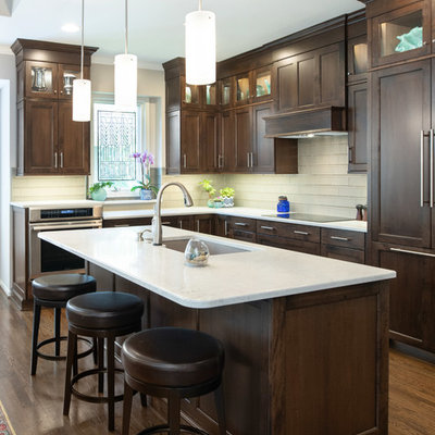 Inspiration for a mid-sized transitional l-shaped medium tone wood floor and brown floor open concept kitchen remodel in Kansas City with shaker cabinets, dark wood cabinets, quartz countertops, glass tile backsplash, an island, an undermount sink, white backsplash, stainless steel appliances and white countertops