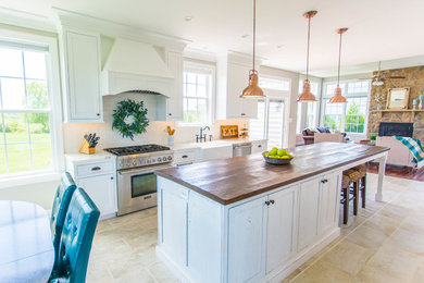 Eat-in kitchen - mid-sized farmhouse galley porcelain tile and beige floor eat-in kitchen idea in DC Metro with a farmhouse sink, flat-panel cabinets, white cabinets, wood countertops, white backsplash, stainless steel appliances, an island and brown countertops