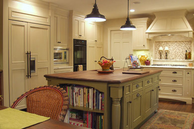 Example of a classic kitchen design in Other with beaded inset cabinets, wood countertops, paneled appliances and an island