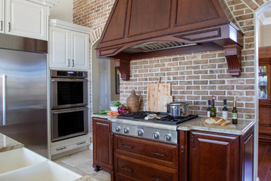 Eat-in kitchen - large cottage single-wall limestone floor eat-in kitchen idea in Jacksonville with a farmhouse sink, raised-panel cabinets, dark wood cabinets, granite countertops, red backsplash, brick backsplash, stainless steel appliances and an island