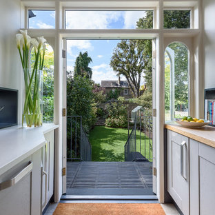Design ideas for a mid-sized modern galley eat-in kitchen in London with recessed-panel cabinets, grey cabinets, wood benchtops, grey splashback, stainless steel appliances, ceramic floors, yellow floor and multi-coloured benchtop.
