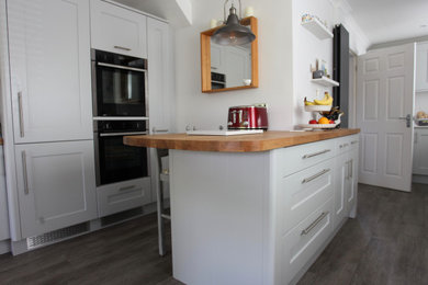 Photo of a medium sized classic galley kitchen/diner in Sussex with a built-in sink, shaker cabinets, grey cabinets, quartz worktops, integrated appliances, vinyl flooring, an island, grey floors and white worktops.