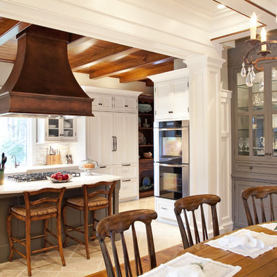 Eat-in kitchen - mid-sized traditional u-shaped limestone floor eat-in kitchen idea in Charleston with shaker cabinets, a farmhouse sink, white cabinets, marble countertops, beige backsplash, matchstick tile backsplash, stainless steel appliances and an island