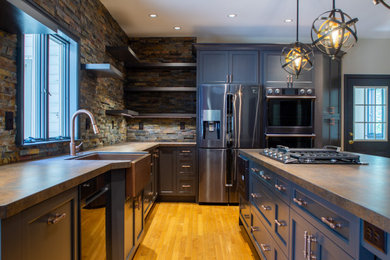 Example of a mid-sized transitional l-shaped light wood floor and beige floor enclosed kitchen design in Wilmington with a farmhouse sink, shaker cabinets, gray cabinets, quartz countertops, brown backsplash, brick backsplash, stainless steel appliances, an island and brown countertops