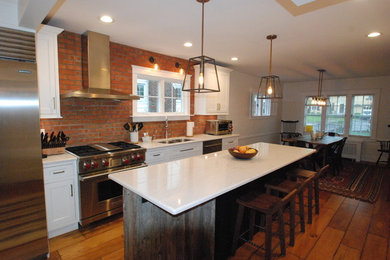 Eat-in kitchen - mid-sized transitional single-wall medium tone wood floor and brown floor eat-in kitchen idea in New York with a double-bowl sink, beaded inset cabinets, white cabinets, quartz countertops, red backsplash, brick backsplash, stainless steel appliances and an island